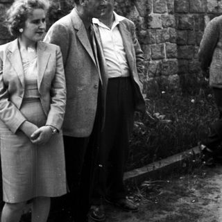 Couple standing near a stone wall in a black and white photo.