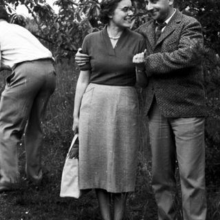 Couple and another person standing in a grassy area.