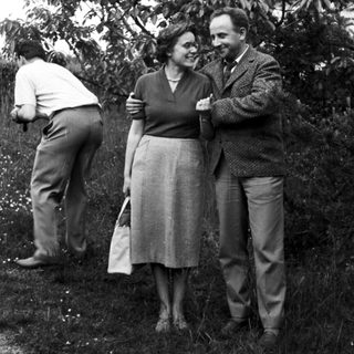 Couple and another person standing in a grassy area.