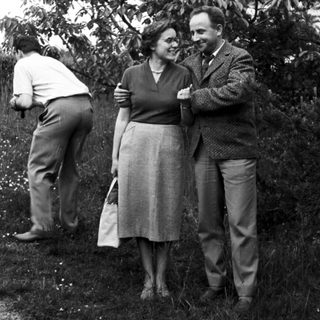 Couple and another person standing in a grassy area.