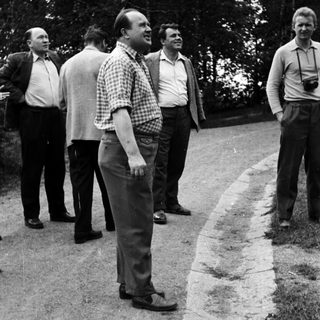 Men standing outdoors on a road, one with a camera.