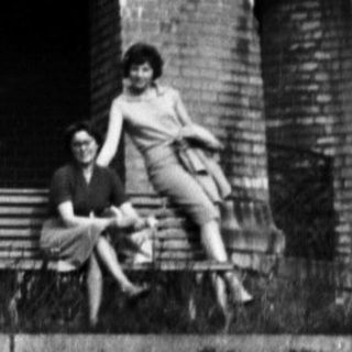People seated near a brick tower with arches.