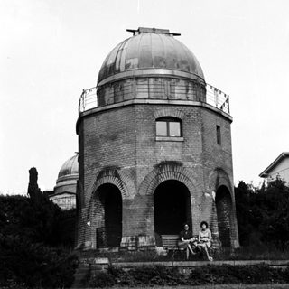 People sit before an observatory with arched doorways.