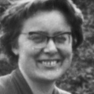 Woman sits on a stone bridge, holding a bag.