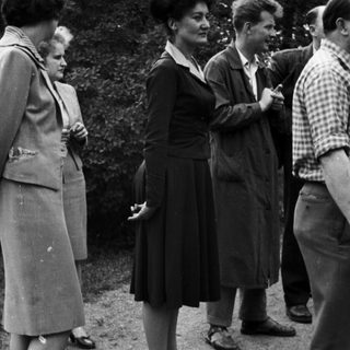 Group of people standing outdoors in a vintage setting.