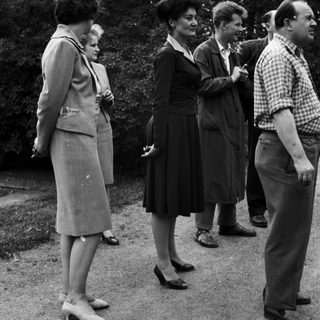 Group of people standing outdoors in a vintage setting.