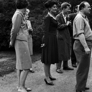 Group of people standing outdoors in a vintage setting.