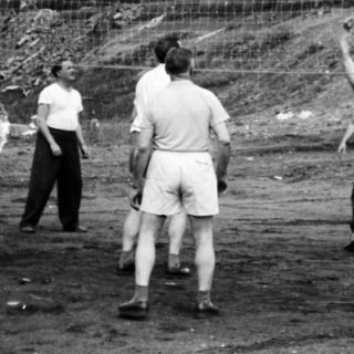 Group playing volleyball outdoors in a rural setting.
