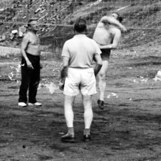Men playing volleyball in an outdoor, rural setting.