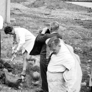 Investigators examine remains and belongings in an outdoor scene.