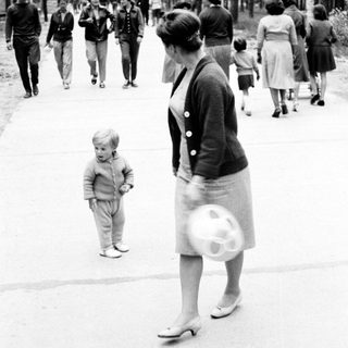 Woman and child walk along a tree-lined path.