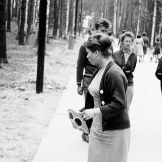 Black and white photo of people walking through a park.