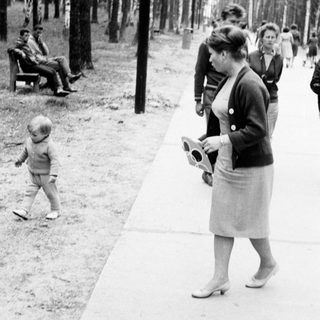 Black and white photo of people walking through a park.
