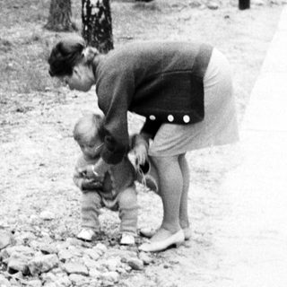 Woman bending down to a child in a park.
