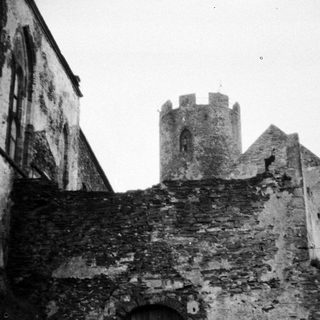 Black and white photo of an old stone tower and wall.