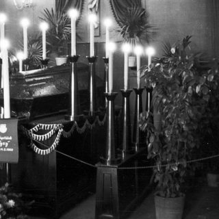 Black and white image of a casket surrounded by candles.