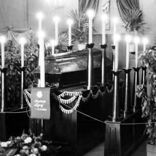 Casket with candles and floral arrangements during a funeral.