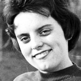 Black and white photo of a smiling woman in a garden.