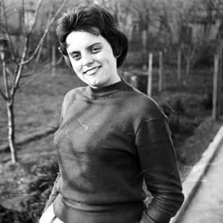 Black and white photo of a smiling woman in a garden.