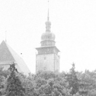 A river flows past trees, with a building in background.
