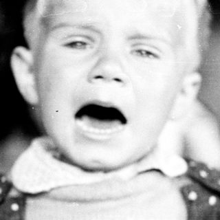 Black and white image of a child with an open mouth.