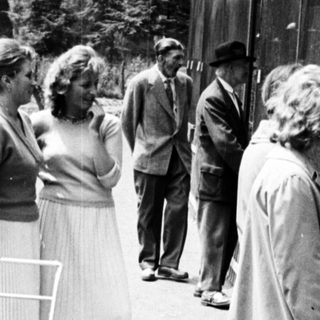 Group of people near a fenced enclosure, likely a zoo.