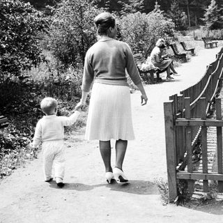 Woman and child walking along a path in a park.