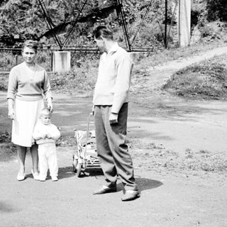Couple with child stand near a vintage wagon.