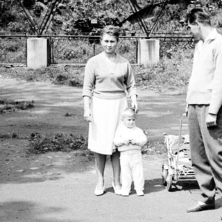 Couple with child stand near a vintage wagon.