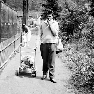 Man walks along a path with a baby carriage.