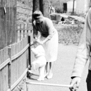 Man walks along a path with a baby carriage.