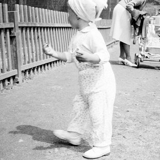 A child walks past adults and a stroller.
