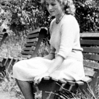 Here's a brief summary of the image: Woman with child near a bench, outdoors.
