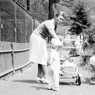 Here's a brief summary of the image: Woman with child near a bench, outdoors.