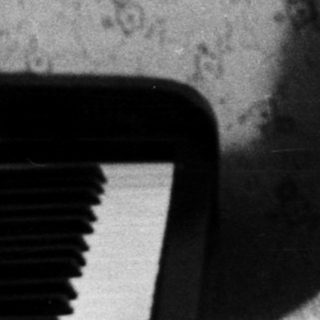 Young man in a coat, seated near a piano.