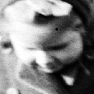 A child runs across a grassy field in a coat.