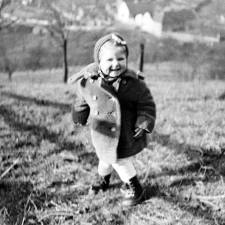 A child runs through a field wearing a coat.