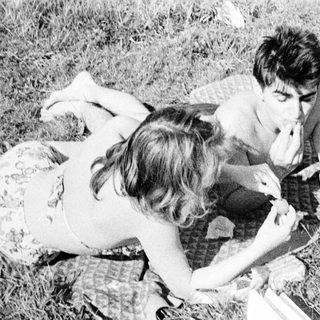 Couple relaxing on a blanket, enjoying a picnic outdoors.