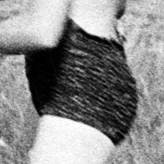 A person in a bikini stands by a lake.