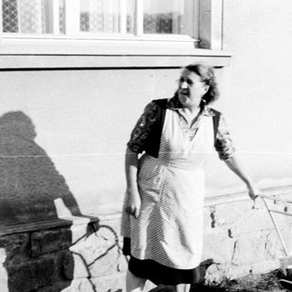 Woman walks along a path, pushing a small cart.
