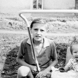 Boy, baby, and a brick wall in a vintage photo.