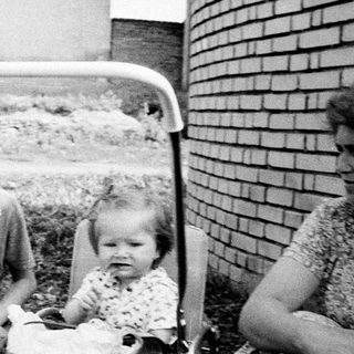 Boy, baby, and a brick wall in a vintage photo.