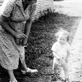 Woman and toddler standing outdoors near a building.