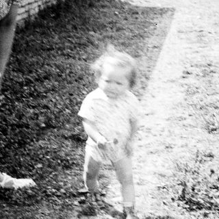 Woman and toddler standing outdoors near a building.