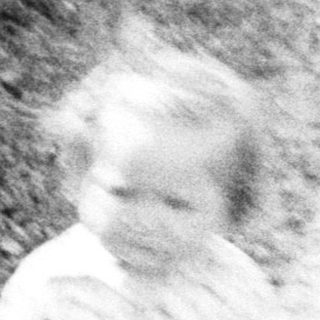 Woman and toddler standing outdoors near a building.