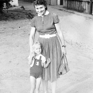 Woman and child stand on a street, vintage photograph.