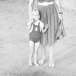 Woman and child stand on a street, vintage photograph.