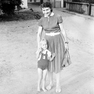 Woman and child stand on a street, vintage photograph.