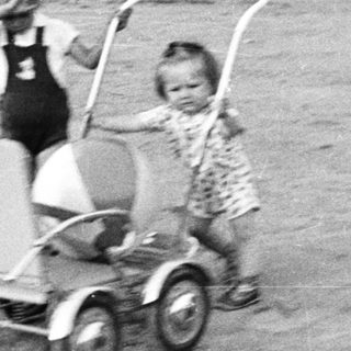 Two children playing with a wagon outdoors.