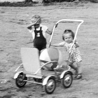 Two children playing with a wagon outdoors.